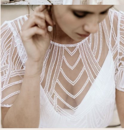 A close detail of a beaded bridal bodice, chevrons of pearl work over sheer tulle.